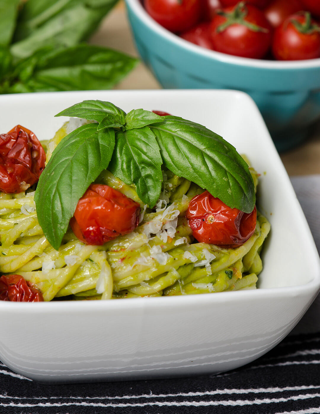 Bowl of pasta tossed with avocado pesto and roasted cherry tomatoes.