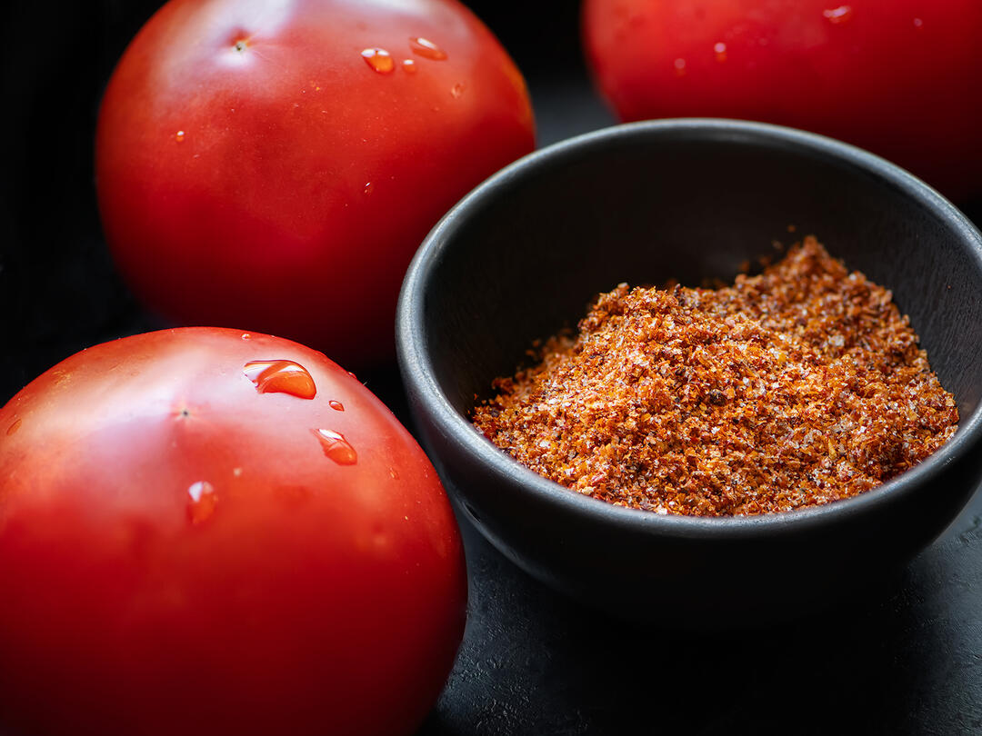 Tomato Salt in a bowl next to fresh tomatoes.