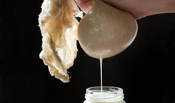 Straining almond milk into a jar.