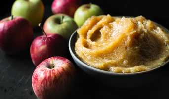 bowl of Honey Roasted Applesauce surrounded by apples