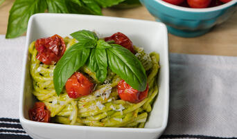 Bowl of pasta tossed with avocado pesto and roasted cherry tomatoes.