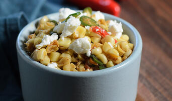 Corn salad with chili butter, peppers, and garnished with feta.