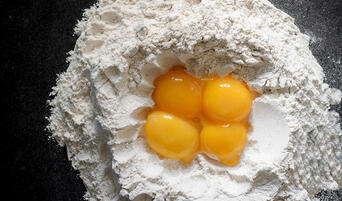 Mound of pasta flour with egg yolks in the center.