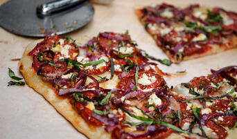 Pizza with roasted heirloom tomato, red onion, and goat cheese.