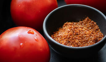Tomato Salt in a bowl next to fresh tomatoes.
