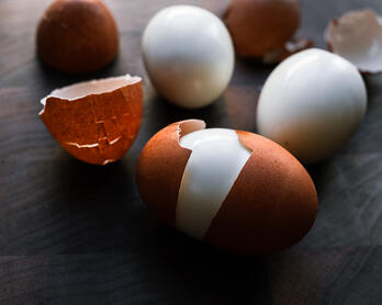Partially peeled hard-boiled eggs plus some shells in the background.