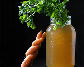 Jar of roasted vegetable stock with carrot.